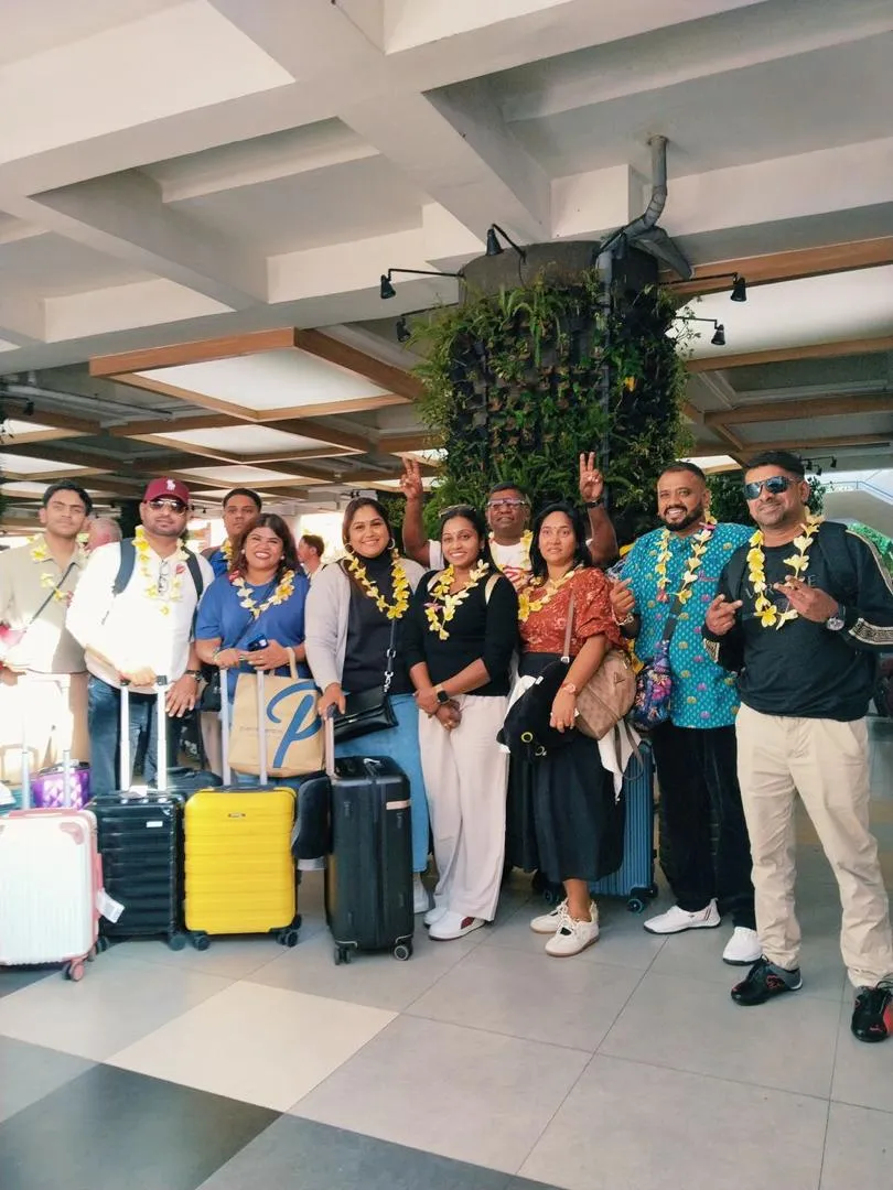 Tour group with luggage posing together at the airport before departing for Bali