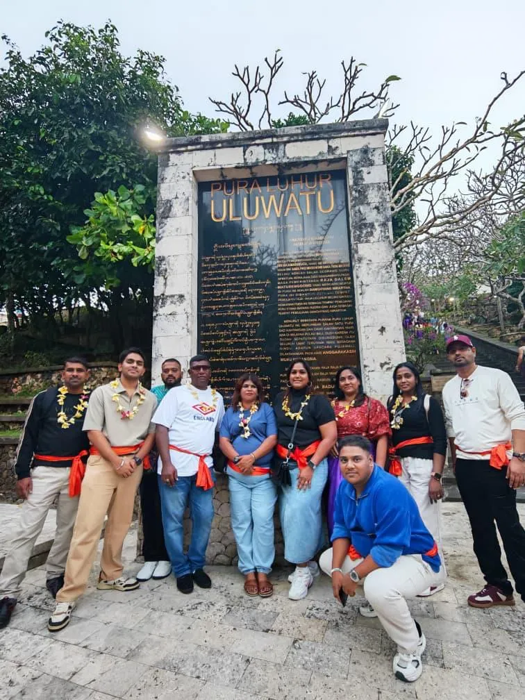 Tour group wearing ceremonial sashes at the entrance of Pura Luhur Uluwatu temple, Bali