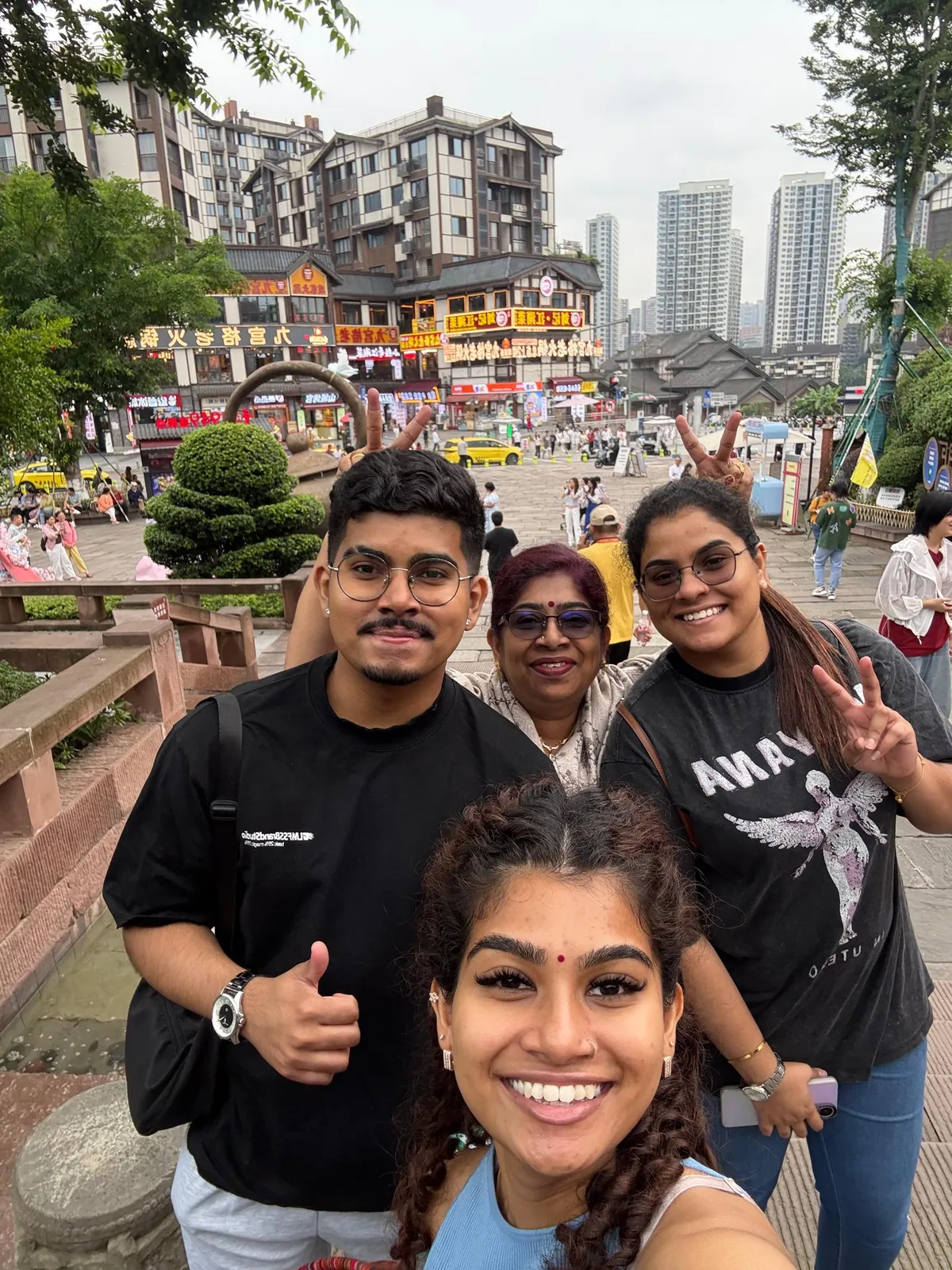 Four travellers taking a selfie together on a China street lined with shops and skyscrapers